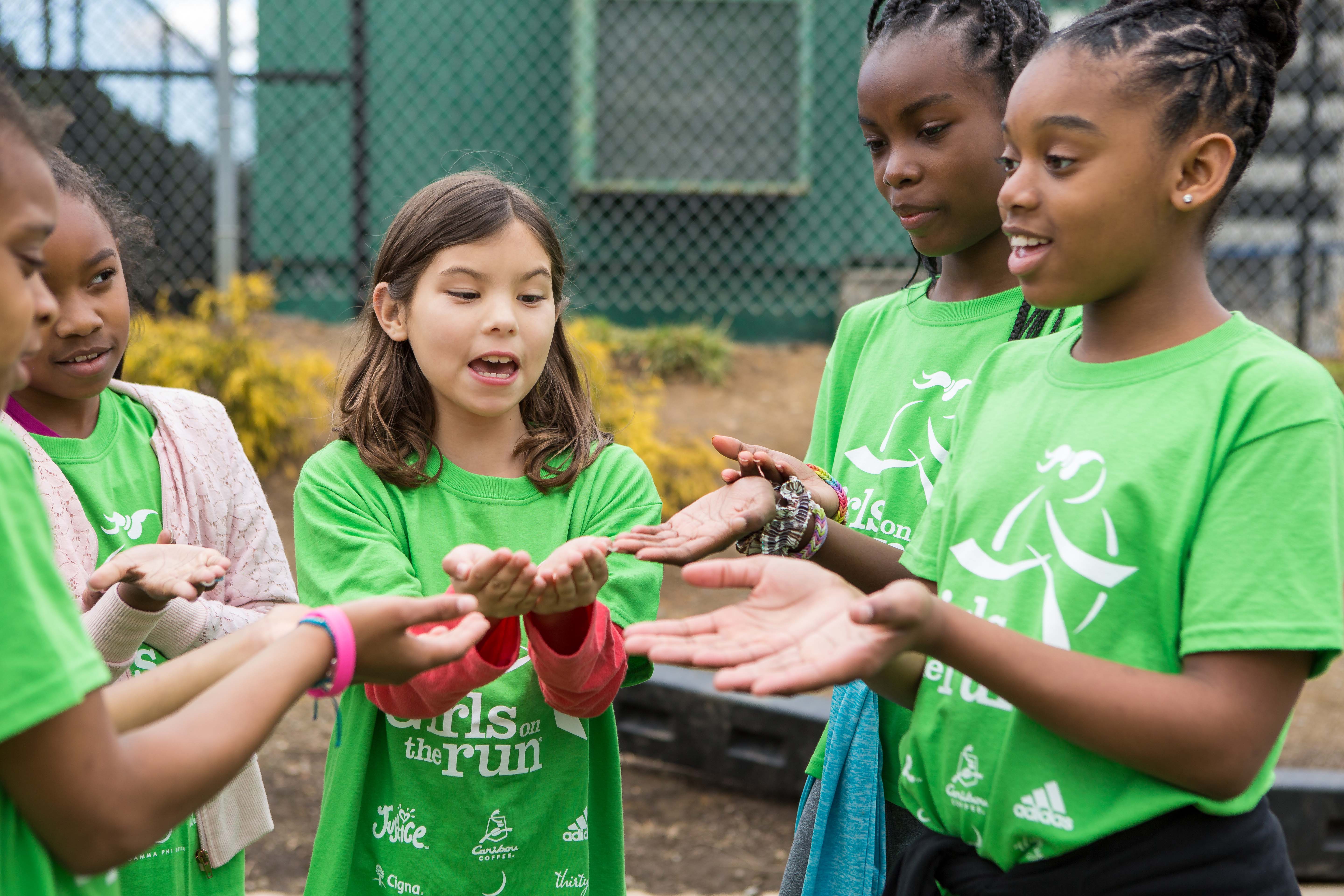 Girls on the Run participants gather with hands open to each other while they doing an activity